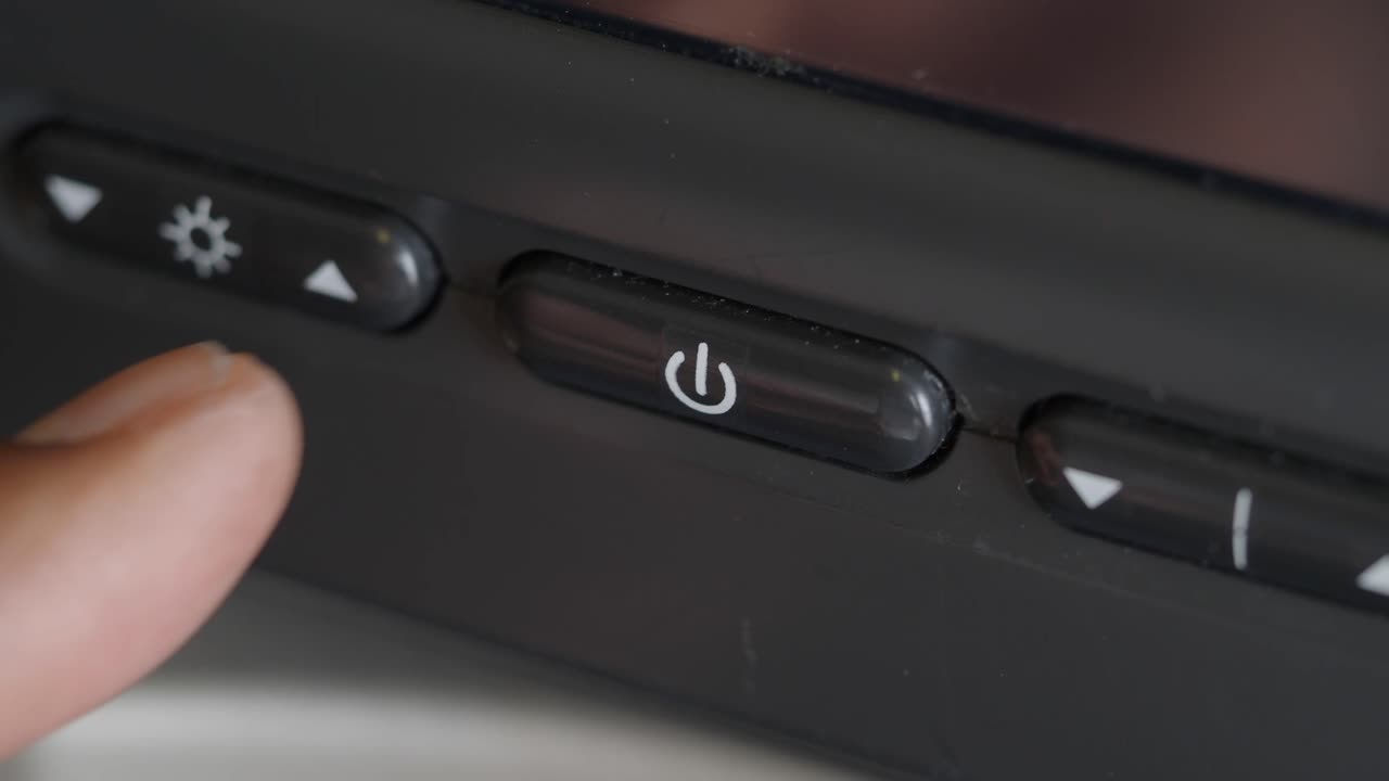 Finger pressing the power button on an electronic device