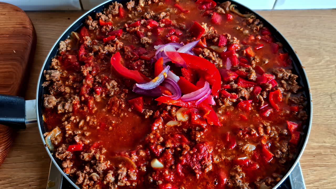 Up-close view of a sizzling ground beef stew with a rich sauce and diced vegetables