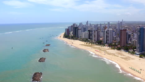 aerial view of jaboatão dos guararapes coast pernambuco northeast brazil with green sea sandy beach blue sky buildings summer vacation vibes boat and parasol.