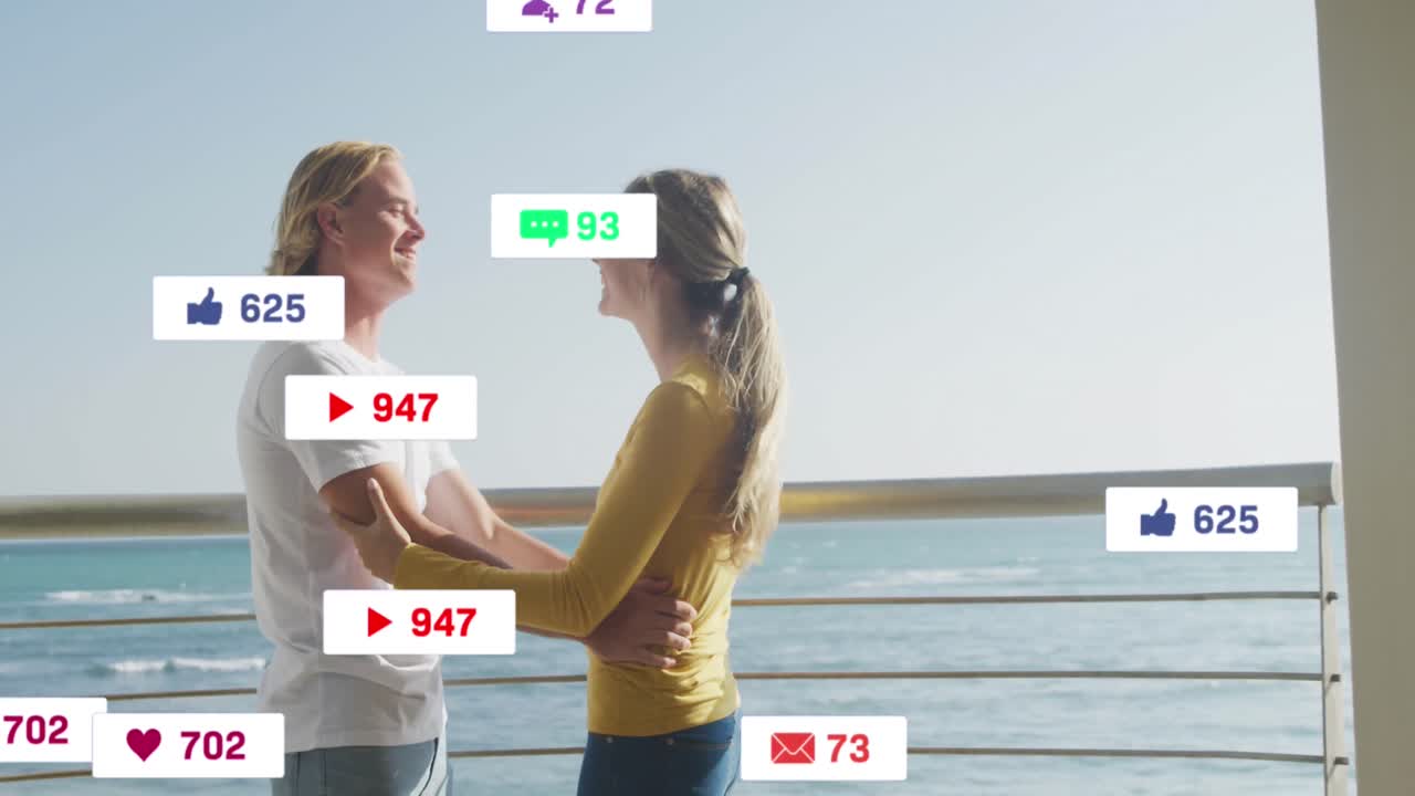 animación de iconos de las redes sociales en pancartas sobre una pareja caucásica enamorada abrazándose en la playa