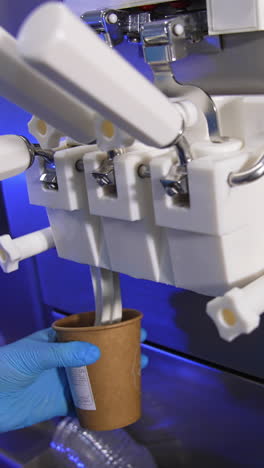 white soft vanilla ice-cream is poured from an automatic machine. sweet dessert is packed into a paper cup. vertical video