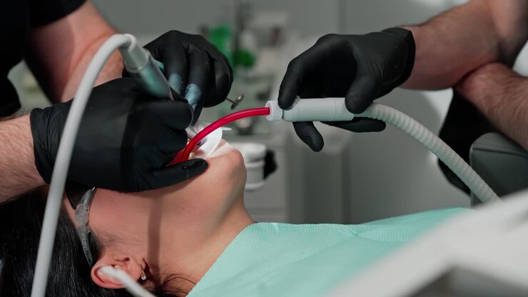 Dentist's hands in black gloves treating woman's teeth. Stomatologist with assistant use modern methods to treat client's tooth. Close-up.