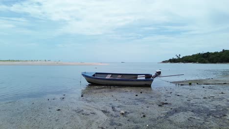 drone video shows traditional small fishing boats anchored near the sandy shoreline of koh phangan, thailand, with clear turquoise water and lush green coastline creating a scenic tropical seascape