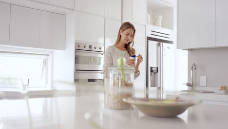 Woman-eating-natural-yogurt-in-kitchen-of-white-clean-luxury-home