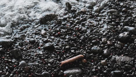 Slow-motion-overhead-view-of-gentle-ocean-waves-flowing-over-small-pebbles