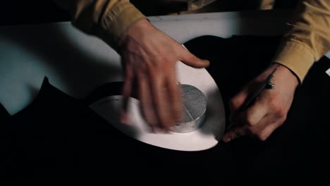 leather craftsman cutting out leather on table at workshop.