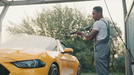 man washing a yellow convertible car at a car wash