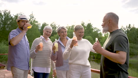 group of senior people dancing and toasting with bottles outdoors