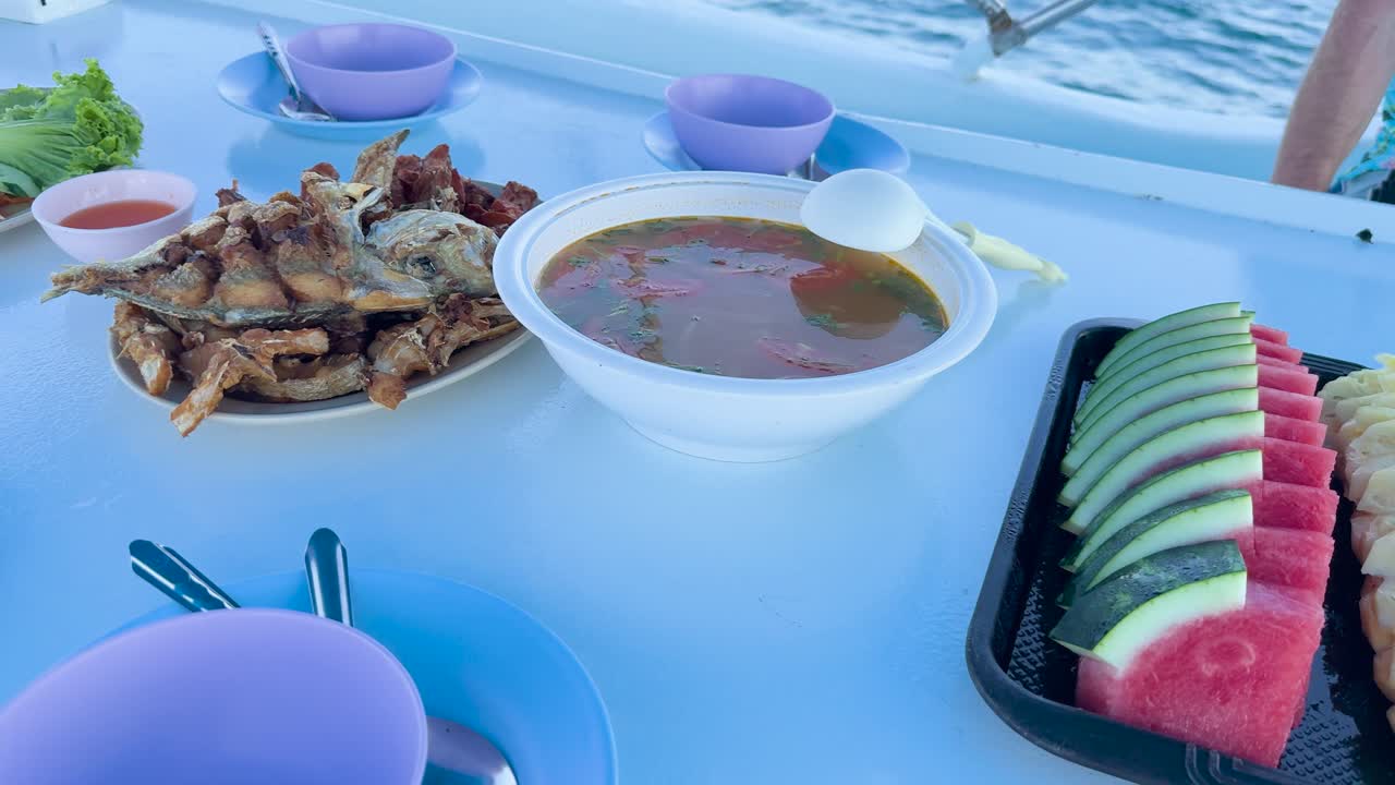 A vibrant meal featuring fresh fruits and dishes on a boat with ocean views in Phuket