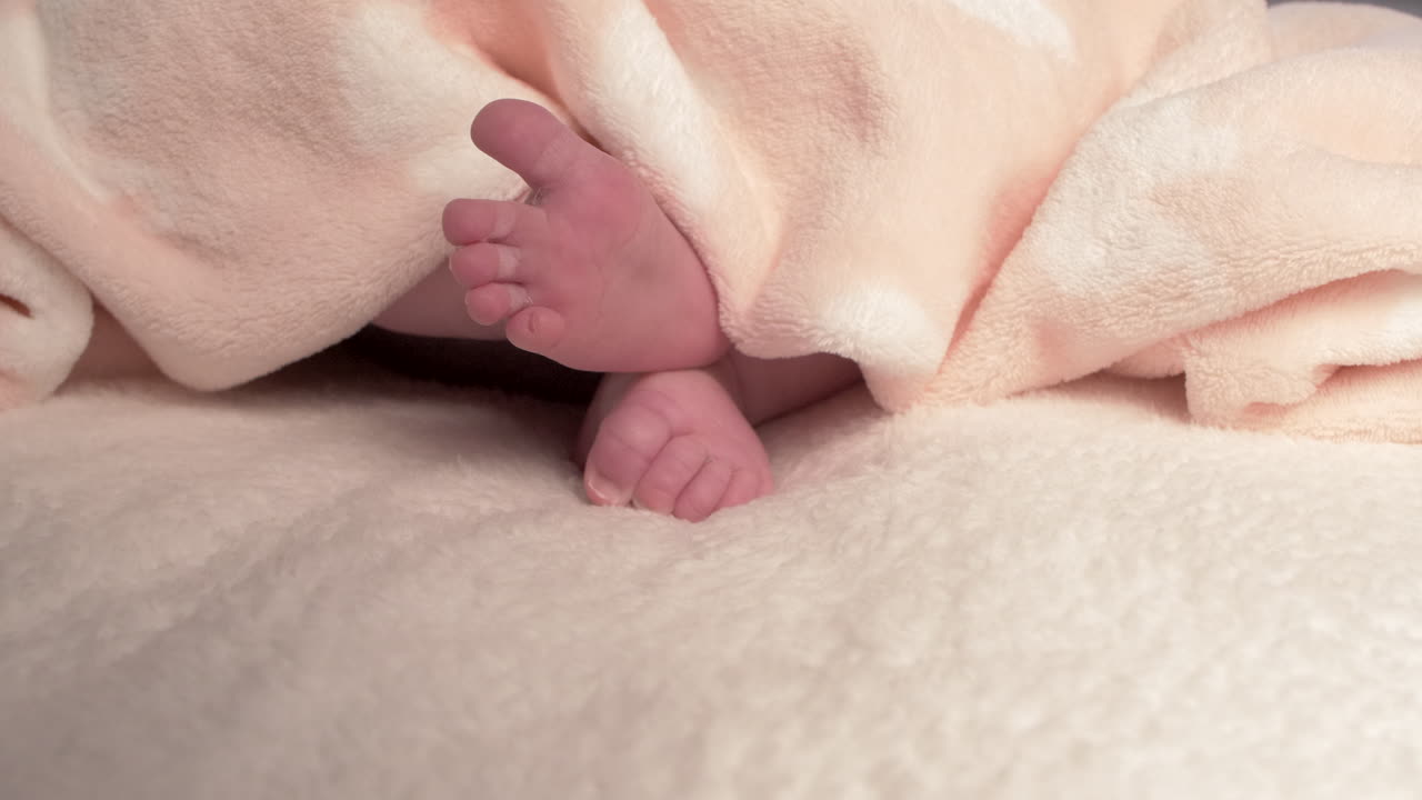 Beautiful Baby newborn is lying in bed and shows hands and feet, mother fandles with baby and covers her up with a cosy coverlet,4k 60p Apple ProRes422, with external Atoms recorder