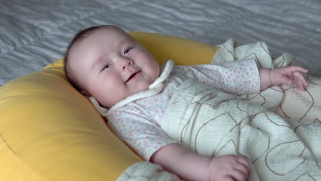 cute infant baby on yellow cushion looking aside