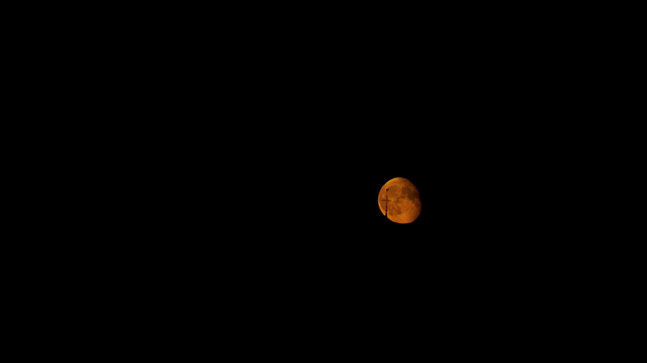 Orange moon in night sky with wind direction arrow in front, time lapse view