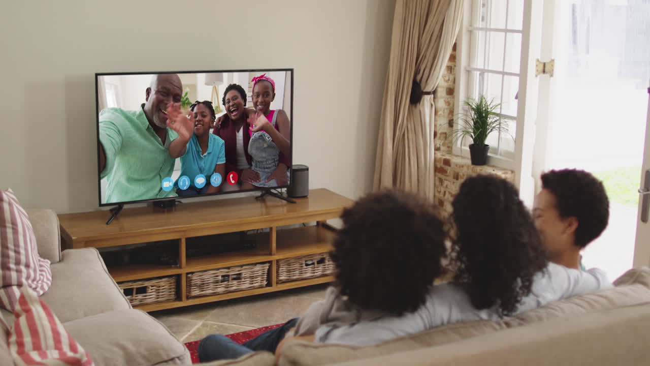 Famiglia afroamericana che fa una videochiamata in TV mentre è seduta sul divano a casa