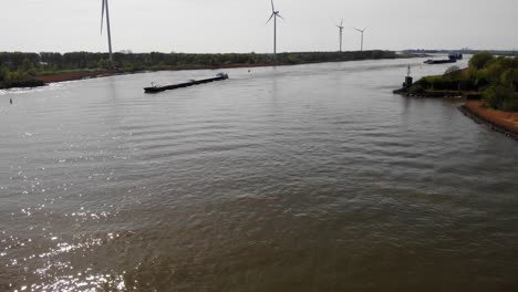 Antena-Sobre-Aguas-Tranquilas-De-Oude-Maas-Con-Barco-Que-Se-Acerca-Y-Todavía-Molinos-De-Viento-En-Segundo-Plano.