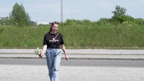 mujer caucásica a mediados de los 30 recogiendo flores silvestres en un día soleado y camina por la calle mostrando un hermoso cubo feliz