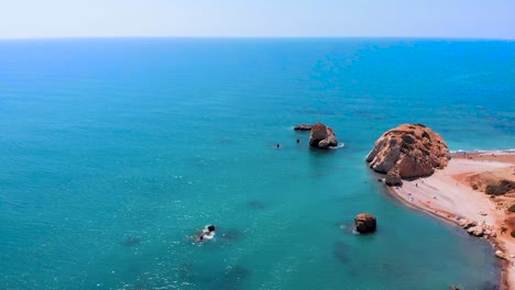 aerial drone shot flying out to sea towards aphrodite's rock in cyprus