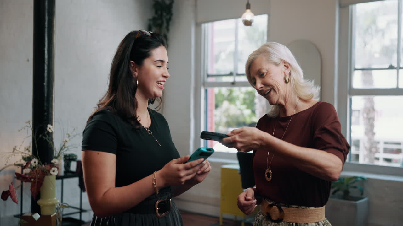 Two Women Laughing and Sharing Content on Smartphones