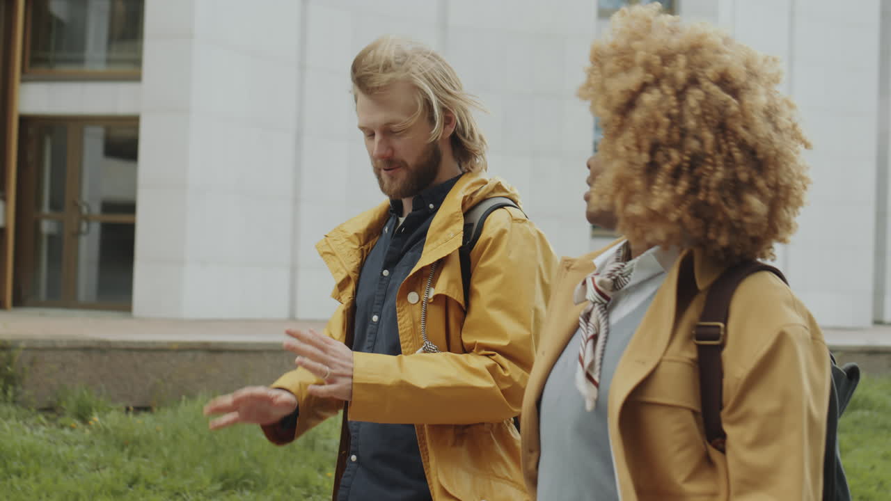 Two young adults walking and talking outdoors on a windy day
