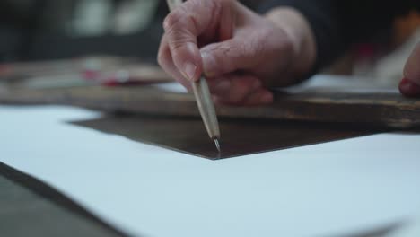 close-up view of an ancient artist hand while painting with engraving technique.