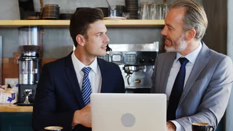 two men watching a laptop and shaking hands