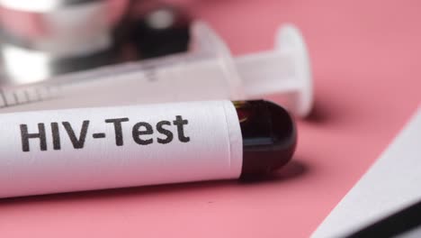 sliding static close up shot of hiv blood test tube and syringe