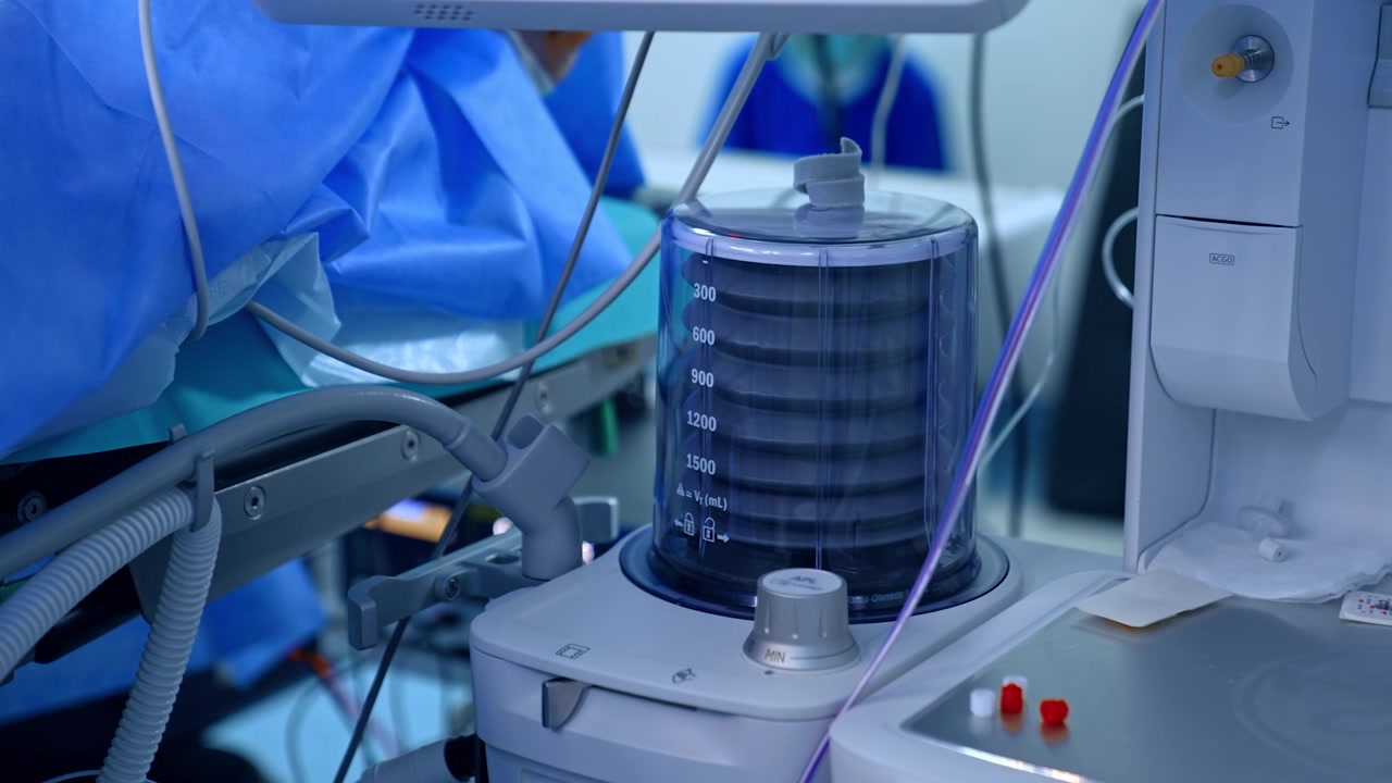 Artificial lung ventilating machine is working in the surgery room. Pump of the equipment is going up and town near the operating table.