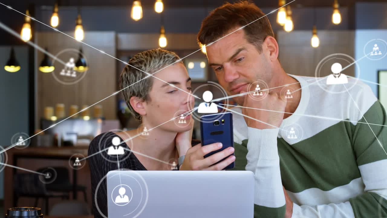 Profile icons connecting with lines over caucasian coworkers discussing over smartphone in office