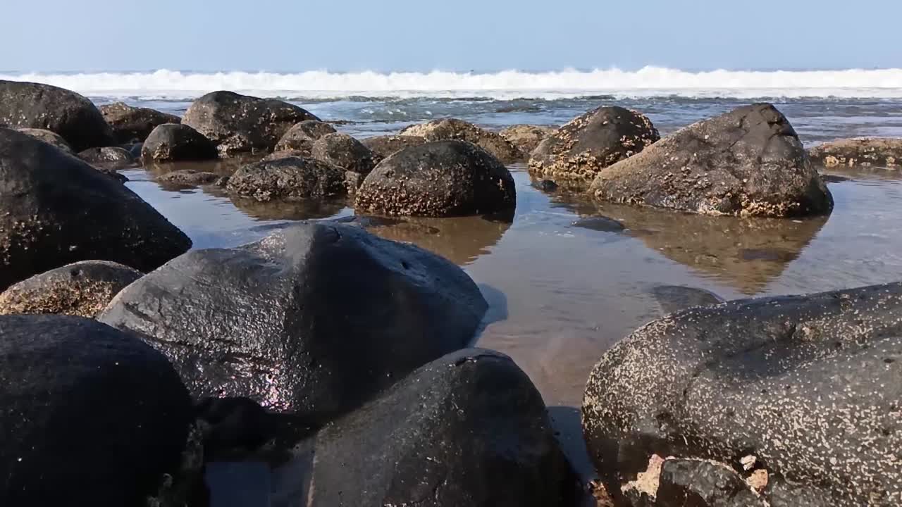 Onde alte che si infrangono contro le grandi pietre sulla spiaggia, Pelabuhan Ratu, Sukabumi, Giava Occidentale