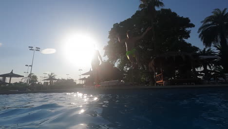 slow motion - teenage boys dive into the outdoor pool