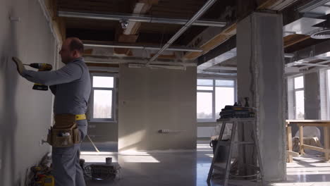 man drilling into a wall during interior construction or renovation