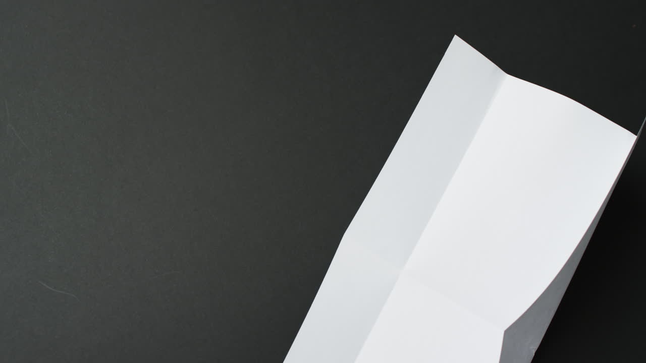 Video of piece of white paper with creases on black background