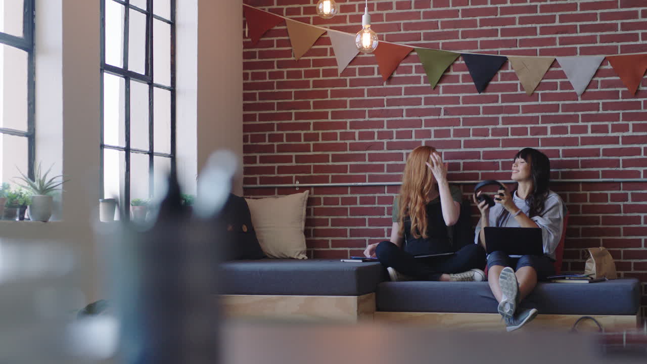 다양한 비즈니스 학생들이 스마트 폰을 사용하는 친구들과 함께 사진을 찍고 소셜 미디어에서 우정을 공유하는 편안한 현대 사무실 직장에서 공부합니다.