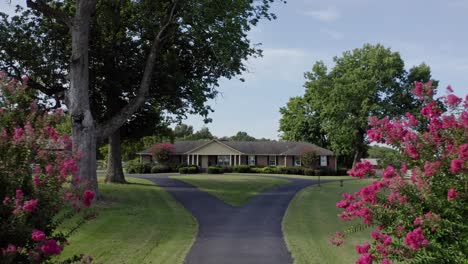 4K-aerial-pushing-in-past-pink-bushes-up-drive-to-idyllic-southern-farmhouse