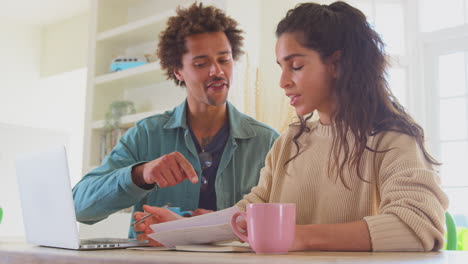 Pareja-Sonriente-En-Casa-Con-Una-Computadora-Portátil-Revisando-Las-Finanzas-Para-Iniciar-Juntos-Negocios-Independientes