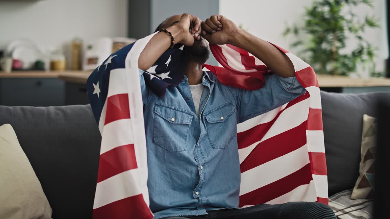 video de un hombre extremadamente feliz viendo la televisión con la bandera de los estados unidos