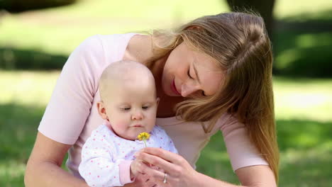 madre feliz sosteniendo a su niña en el parque