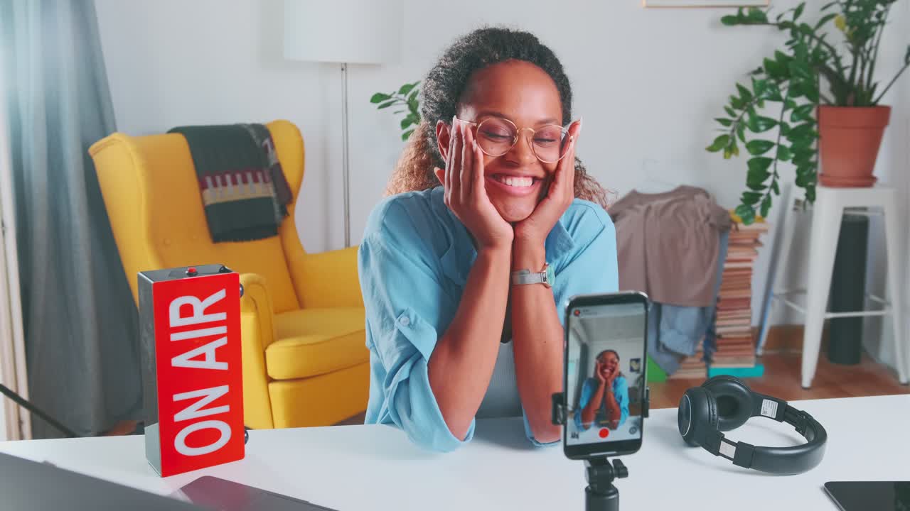 joven mujer afroamericana filma un video blog en el teléfono móvil se sienta en el apartamento