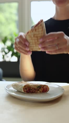 una mujer comiendo un envoltorio.