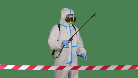 the view from behind the signal tape a man in a protective uniform and a respirator walks and disinfects the fenced area. isolated on a green screen chroma key. slow motion. close up