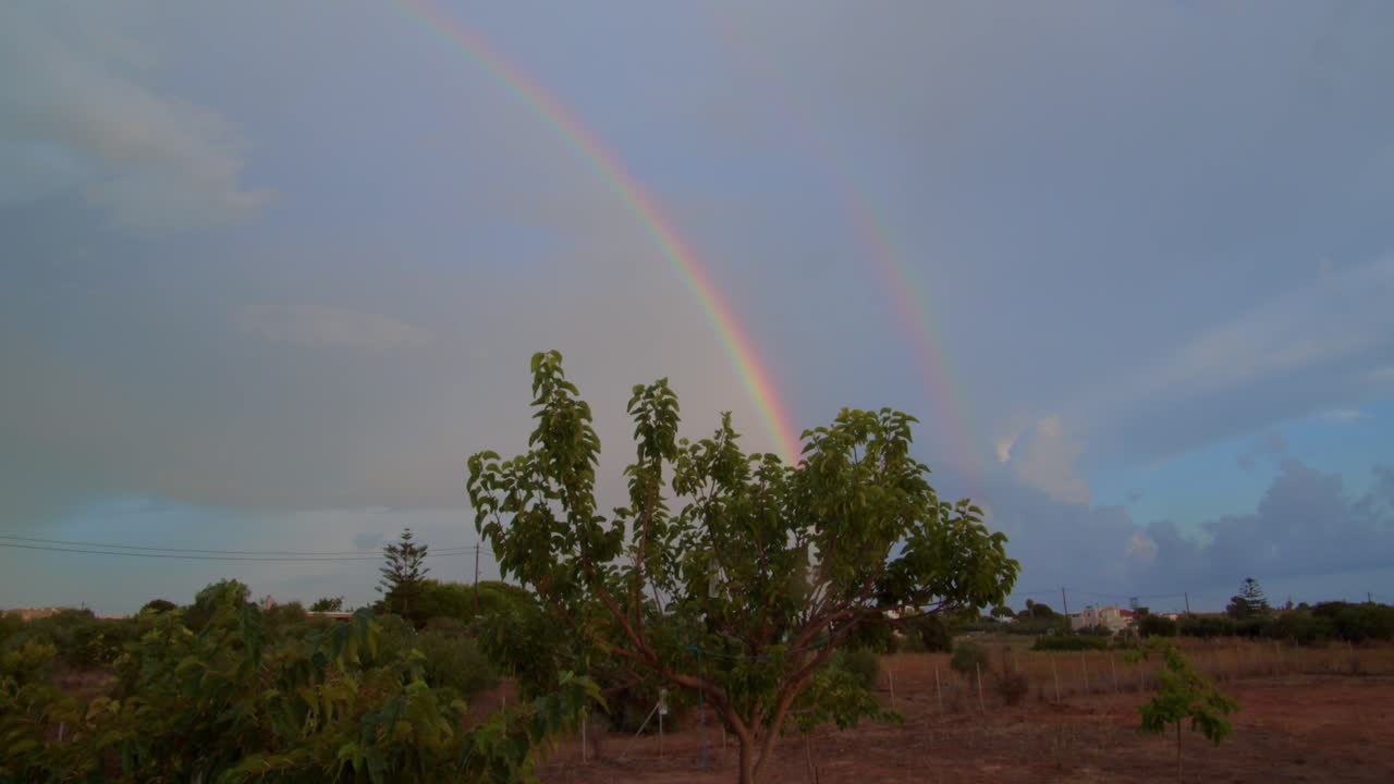 hermoso doble arco iris cinematográfico sobre los árboles del pueblo rural
