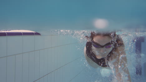 Underwater-Shot-Of-Woman-Swimming-In-Indoor-Pool