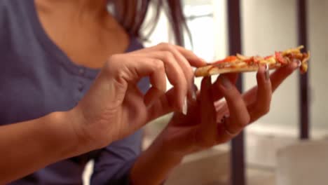 mujer hispana sonriente comiendo pizza