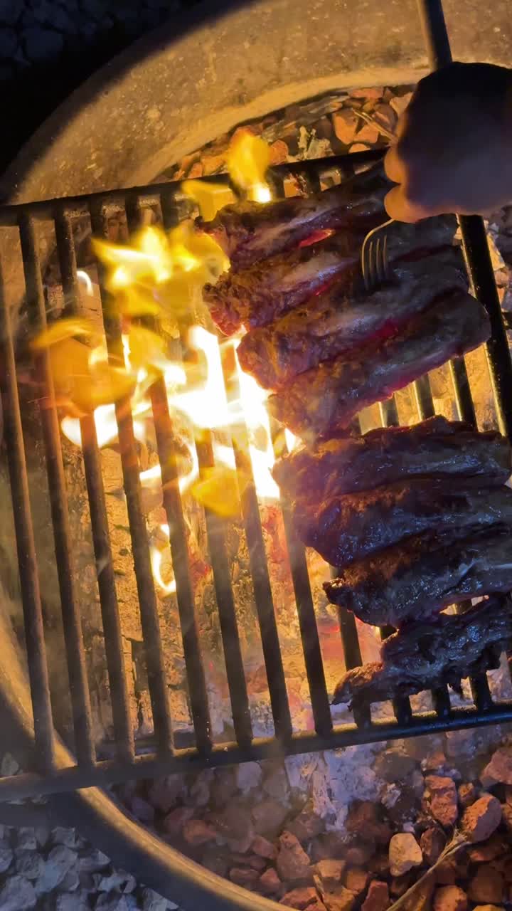 Carne che griglia sul fuoco aperto di notte