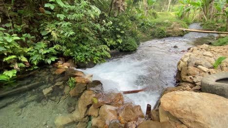 Closeup-of-the-gurgling-stream-of-running-water-in-Kali-Umbul-Gumuk-in-Magelang,-Indonesia,-a-river-of-clear-springs-showing-the-riverbed