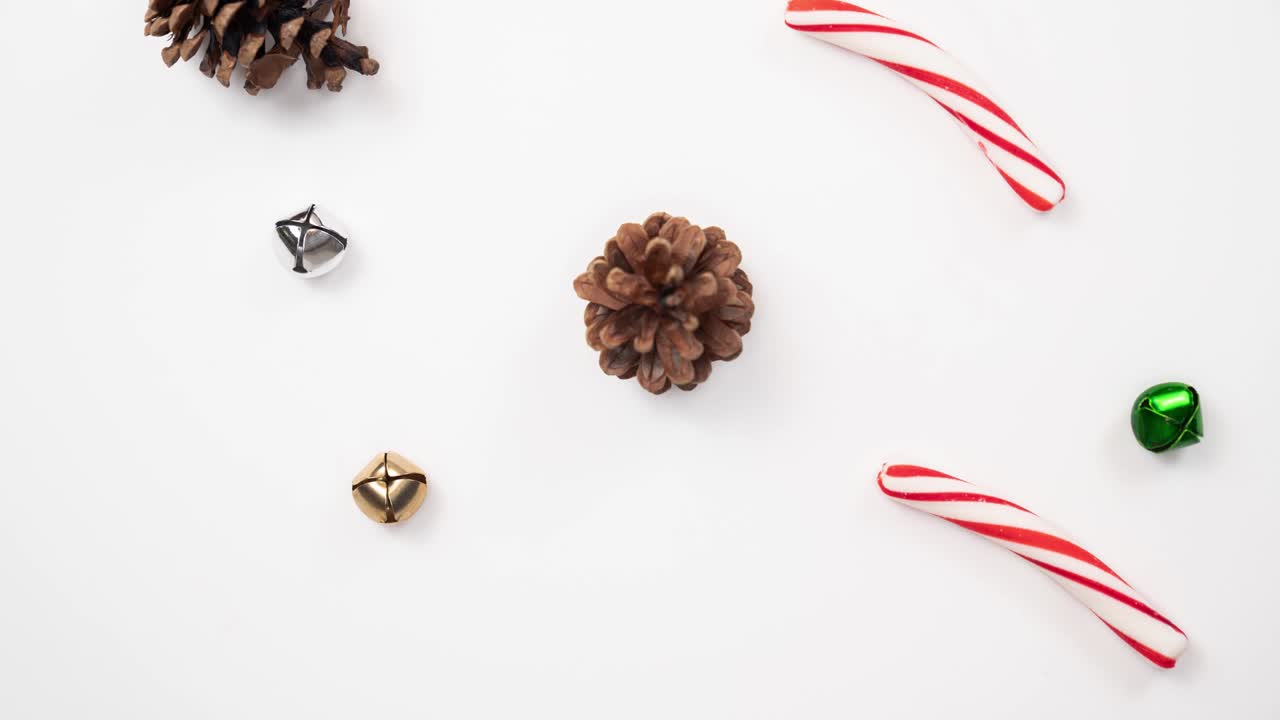 hermoso bucle de fondo de vacaciones de conos de pino, palos de caña de caramelo, y campanas verdes, doradas y plateadas añadiendo y quitando lentamente una a la vez.
