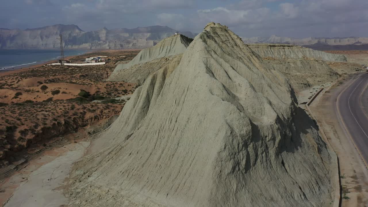 вид с воздуха на выветрившийся эрозированный склон холма рядом с пустой дорогой у береговой линии в белуджистане