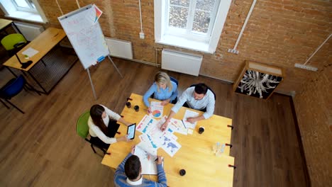 reunión de negocios en el loft espacio compartido. equipo hablando, mujer gerente dando dirección a la gente. vista superior.