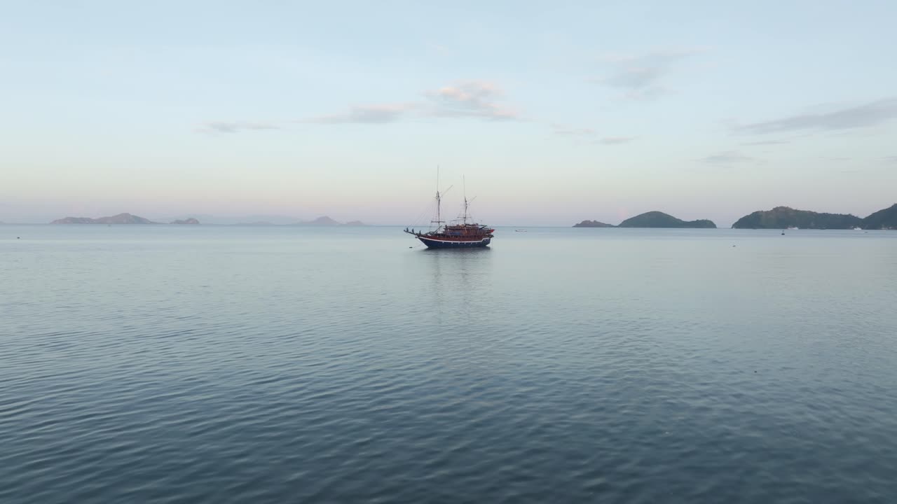 Gün doğumuyla sakinleşen denizde dinlenen tur sandalları, Labuan Bajo, Flores, Endonezya