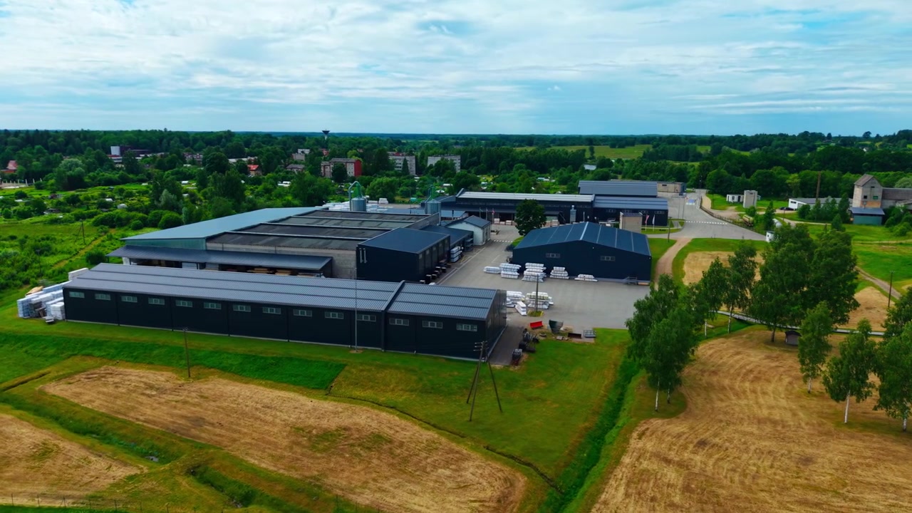 Bredt luftfoto af industrielt træforarbejdningsområde ved siden af landlige marker