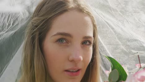 portrait of happy caucasian woman with veil on sunny day at wedding